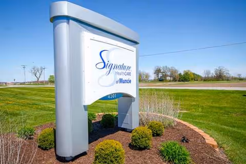 Outdoor sign for Signature HealthCARE of Muncie surrounded by shrubs and landscaping
