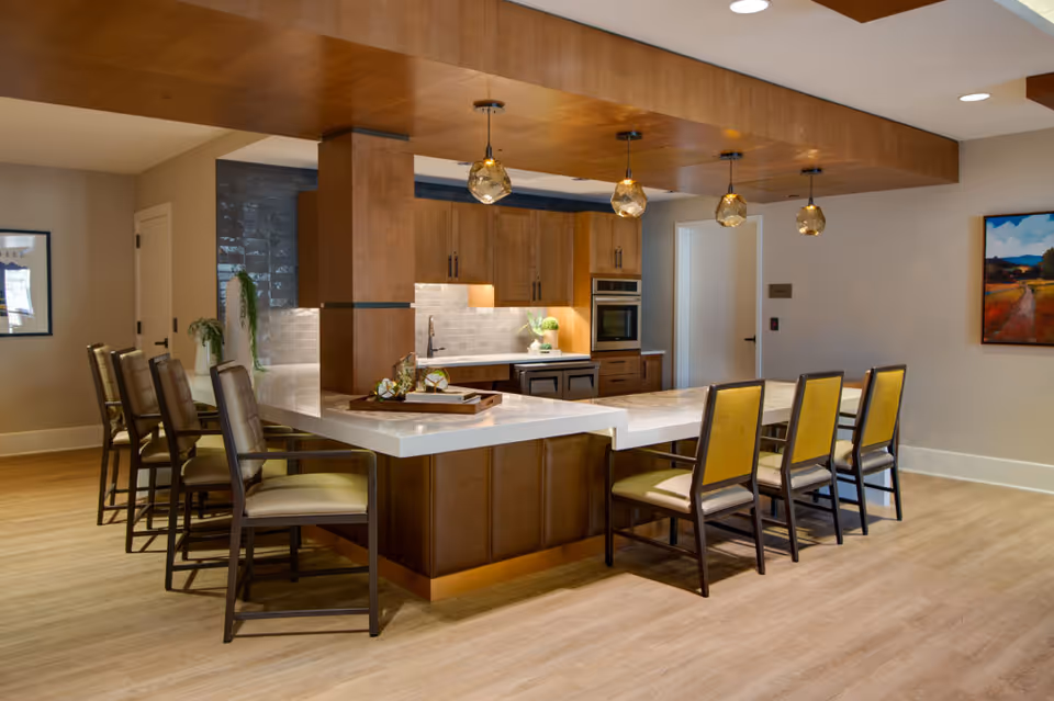 Communal kitchen with a large marble-topped island, pendant lights, and seating.