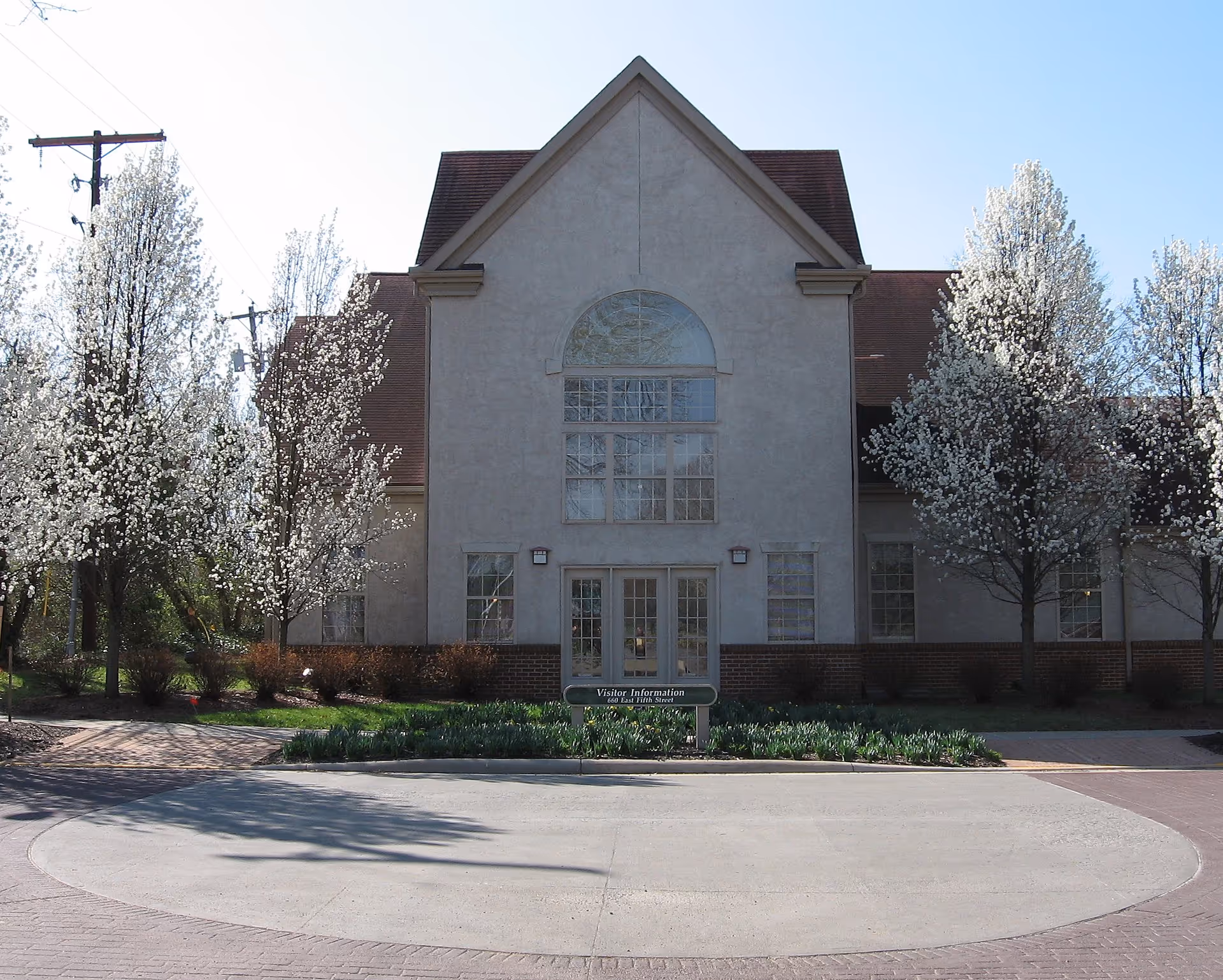 Front view of a Bristol Village building with blossoming trees and a circular driveway.