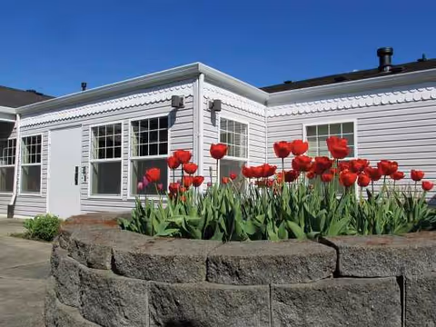 White single level senior living building with red tulips planted in a stone planter