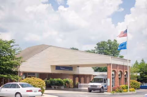 Front exterior view of Signature HealthCARE of Fentress County with entrance canopy and flags.