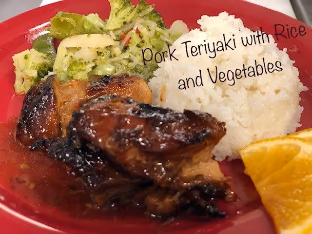 A plate with pork teriyaki, white rice, mixed vegetables including broccoli, and a slice of orange on a red plate. Text on the image reads 'Pork Teriyaki with Rice and Vegetables'.