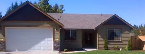 Front view of a single-story house with a two-car garage and manicured lawn.