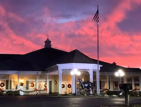 Front exterior view of Crescent Place Assisted Living at dusk with porch lights and flag.