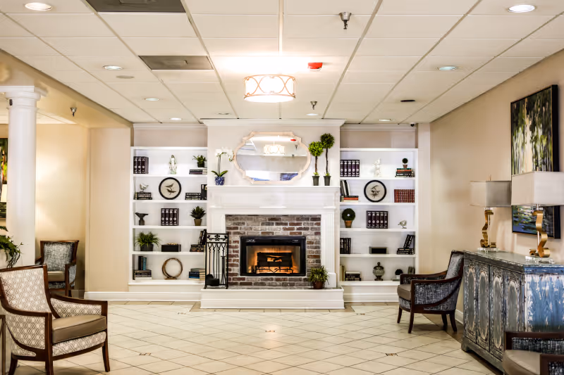 A bright common room with a central fireplace flanked by built-in bookshelves and seating.