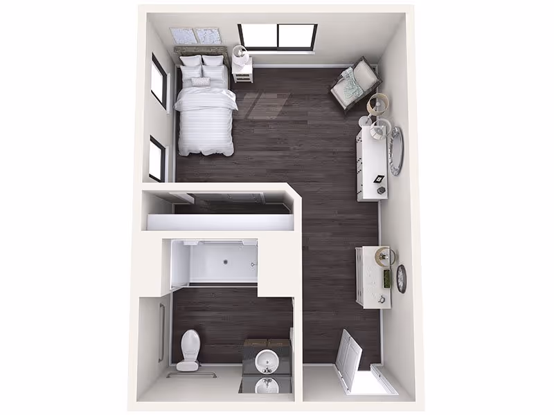 Top-down view of a small apartment layout featuring a bedroom area with a bed, nightstand, armchair, and dresser. The layout also includes a bathroom with a toilet, sink, and shower. The flooring is dark wood throughout the living and bedroom areas, with tile in the bathroom.