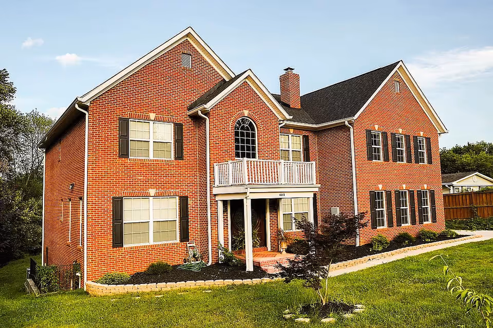 Red brick, two-story assisted living building with white balcony and landscaped front yard.