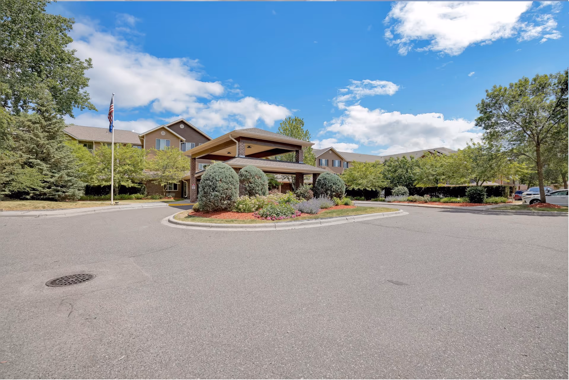 Exterior view of a senior living Lodge at White Bear with landscaped circular driveway.