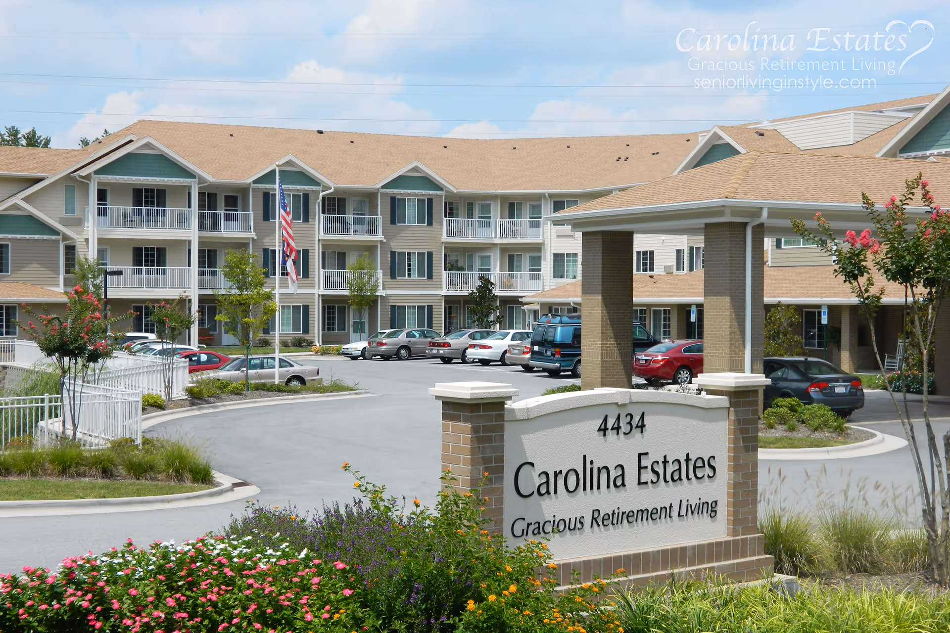 Entrance sign and covered porte-cochere of Carolina Estates retirement community with the three-story residence, parking lot, and landscaping visible.