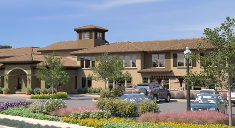 Exterior view of Oakmont of Concord with trees, flowers, and parked cars.