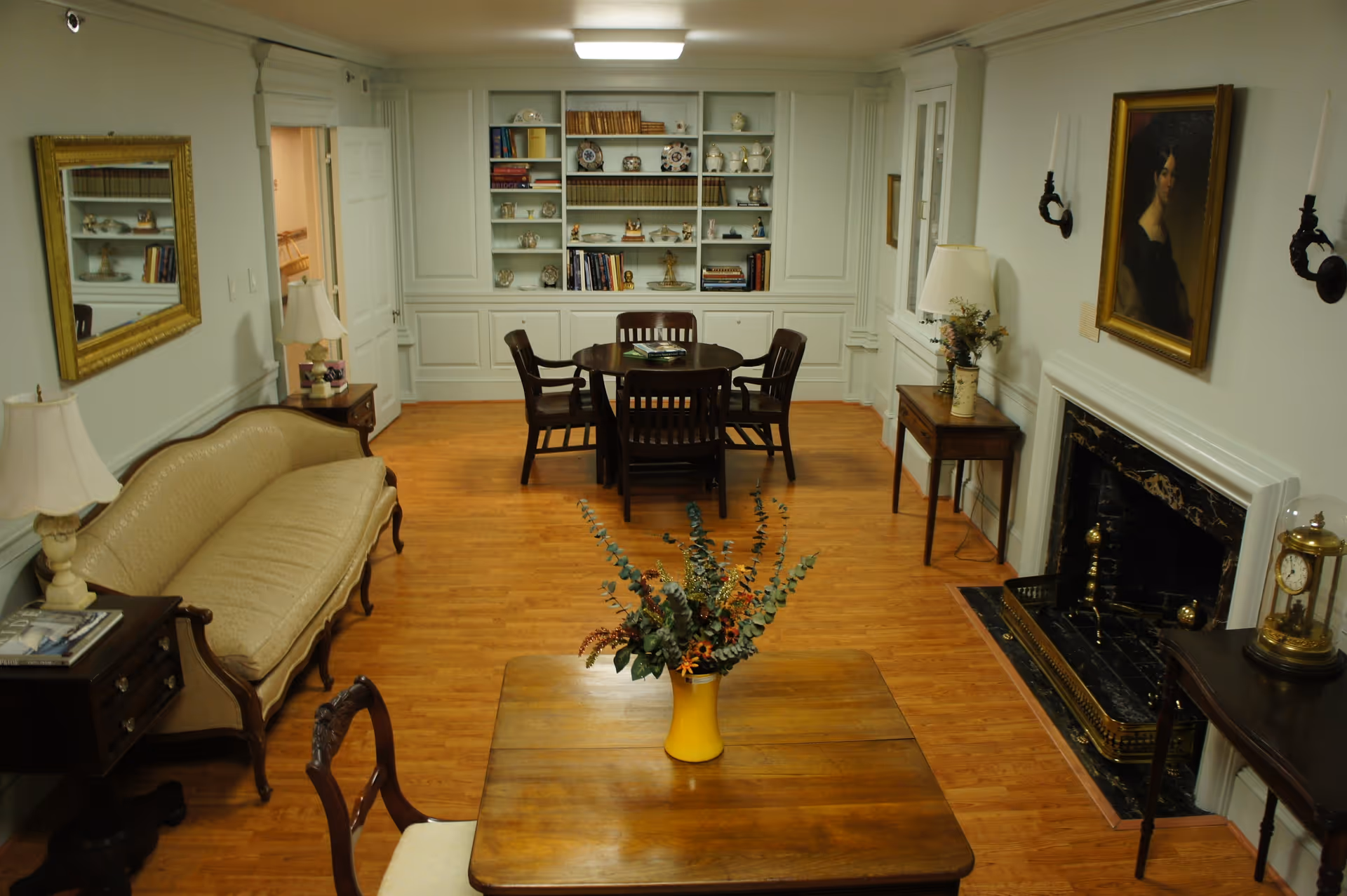Well-appointed common room with hardwood floors, a sofa and chairs, a dining table, built-in bookshelves and a fireplace.