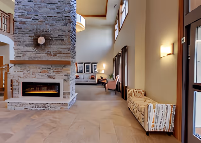 Spacious communal lounge with a large stone fireplace, high ceilings, and seating along the walls.