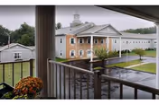 Balcony view of a beige senior living facility with white trim and front entrance.