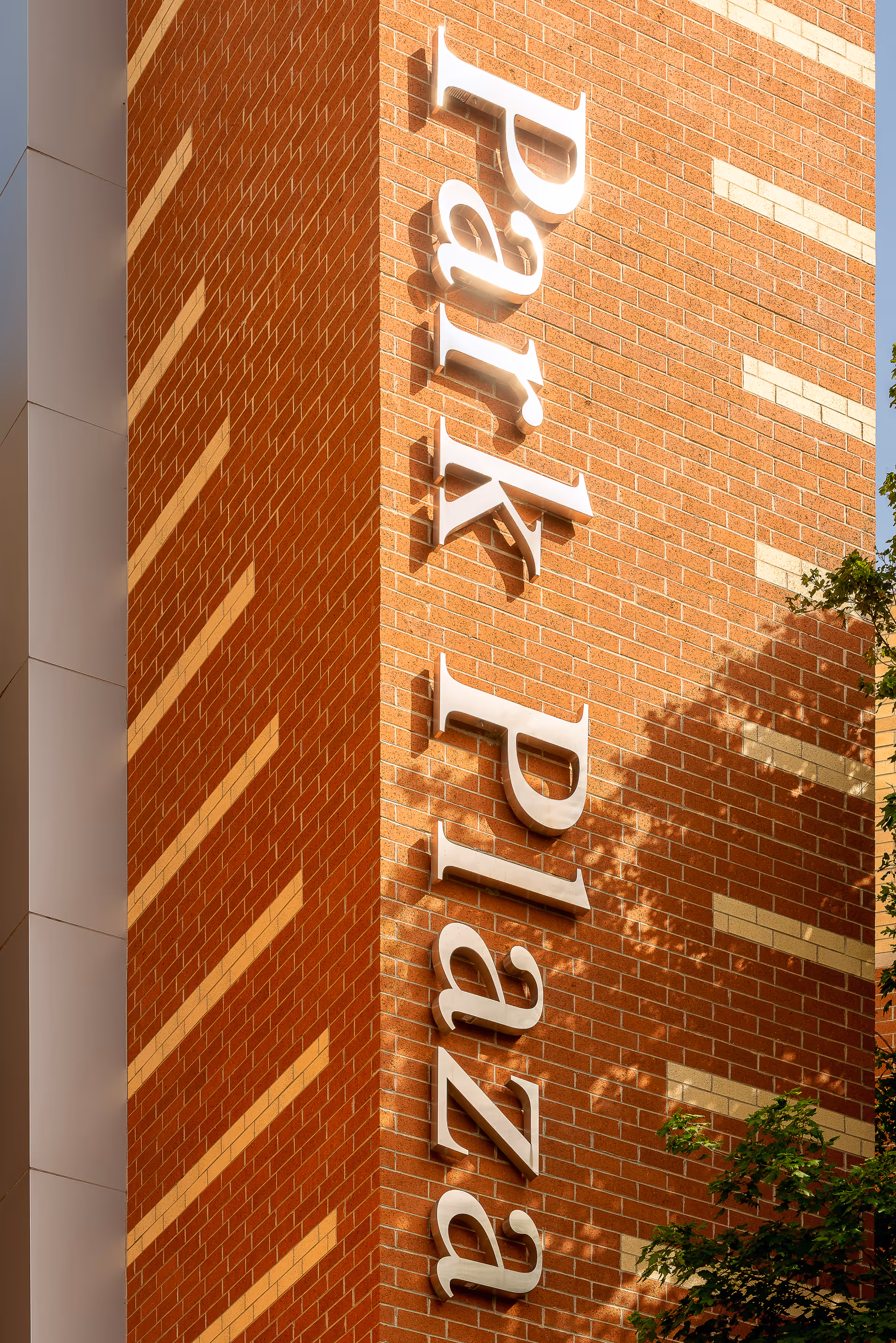 Brick building facade with large vertical white letters reading "Park Plaza" mounted on it.