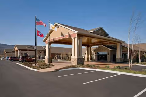 Entrance of a senior living facility with a covered drop-off and flags