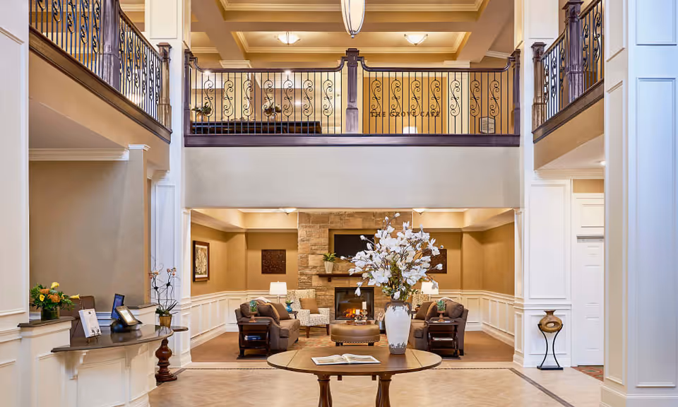 Spacious two-story lobby lounge with seating grouped around a stone fireplace and a central table holding a vase of flowers.