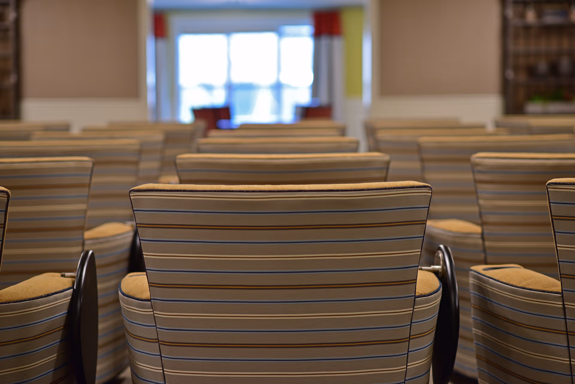 Rows of striped upholstered chairs arranged in a communal seating area facing a bright window.