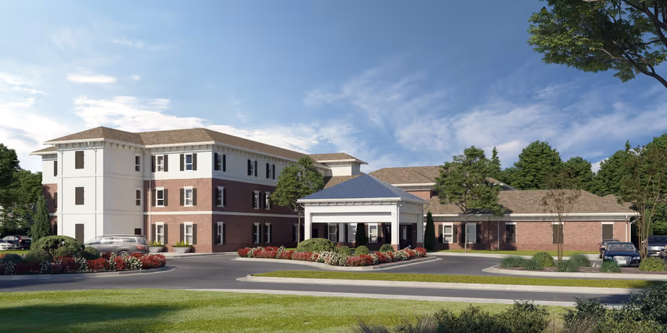 Exterior view of a multi-story senior living building with a covered entrance and landscaping.