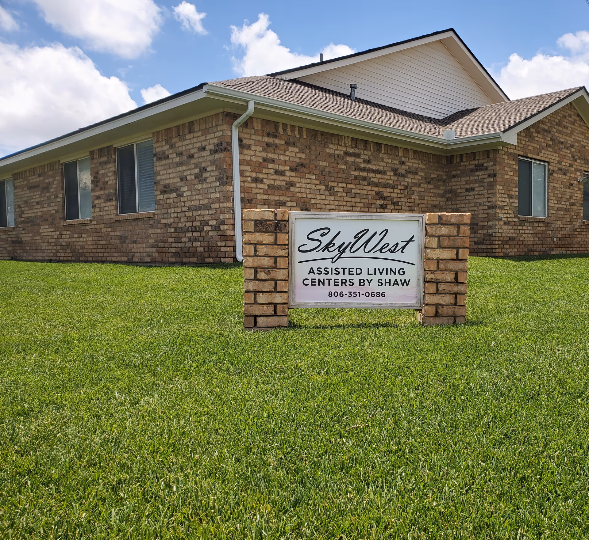A single-story brick building with a SkyWest Assisted Living sign on a grassy lawn.