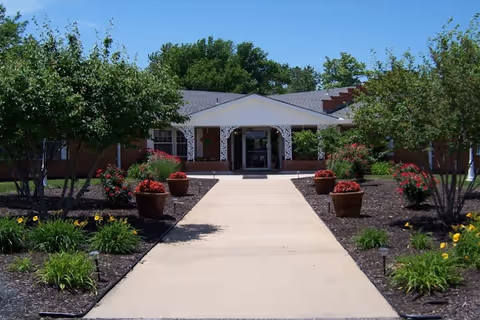 Front entrance of Heritage Avonlea of Olathe, with a central walkway and potted plants.