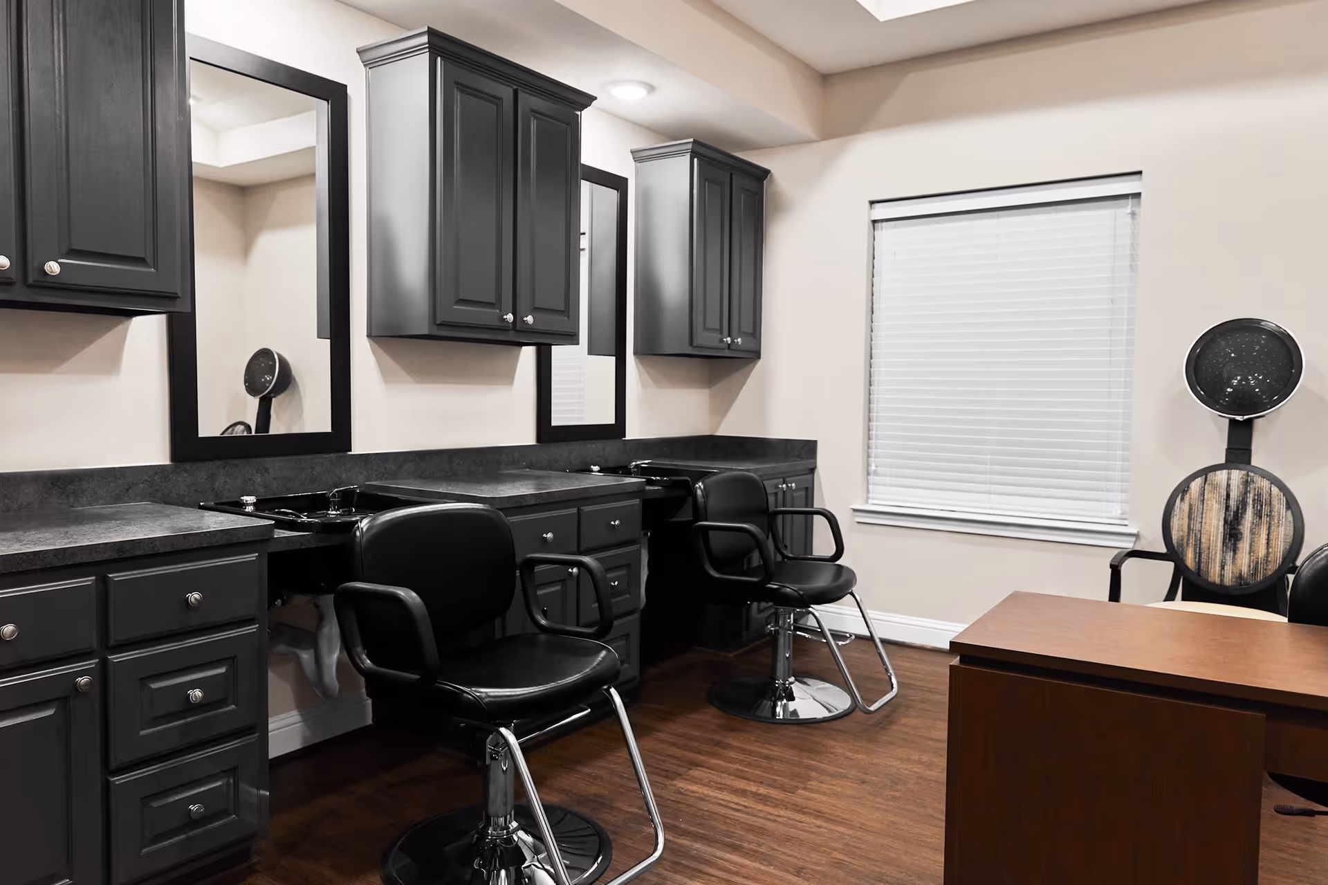 Interior salon room with styling chairs, sinks, mirrors, and dark cabinetry.