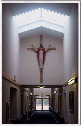 Interior corridor in a senior living facility featuring a crucifix on the wall.