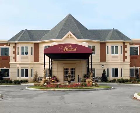 Front view of The Bristal Assisted Living building with a burgundy entrance awning.