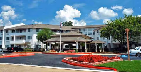Exterior view of Holiday Summerfield Estates with a porte-cochère and red flower beds.