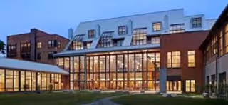 Modern senior living facility exterior with glass-front entrance and brick façade.