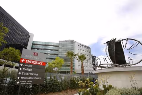 Exterior view of East Los Angeles Doctors Hospital with emergency sign and sculpture.