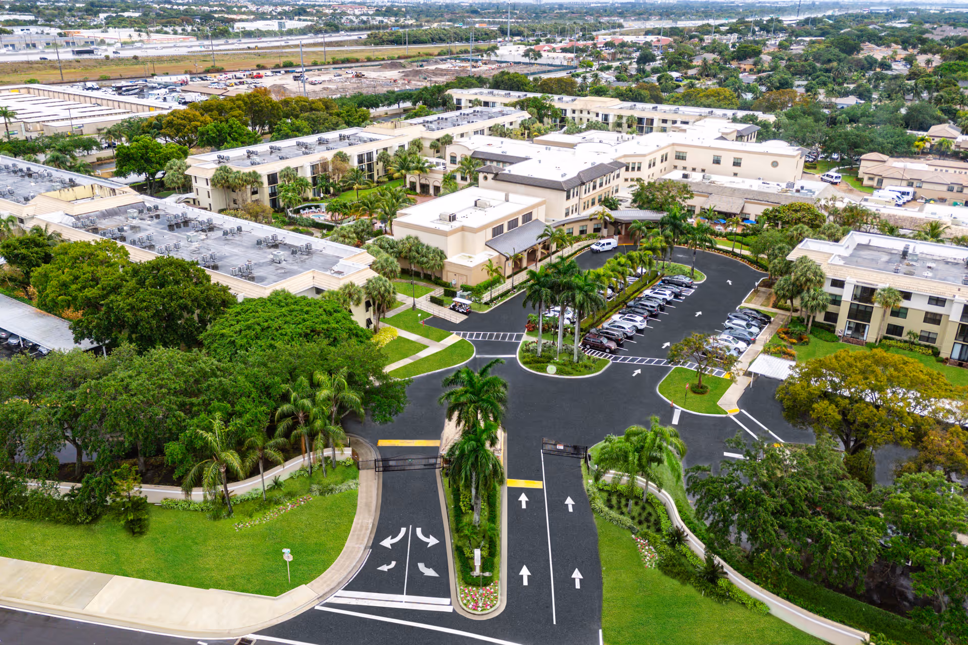 Aerial view of the Cascades at Delray Beach campus showing the entrance drive, parking lot, multiple buildings and surrounding landscaping.