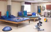 Therapy room with mats, balance equipment, and exercise gear in a senior facility.