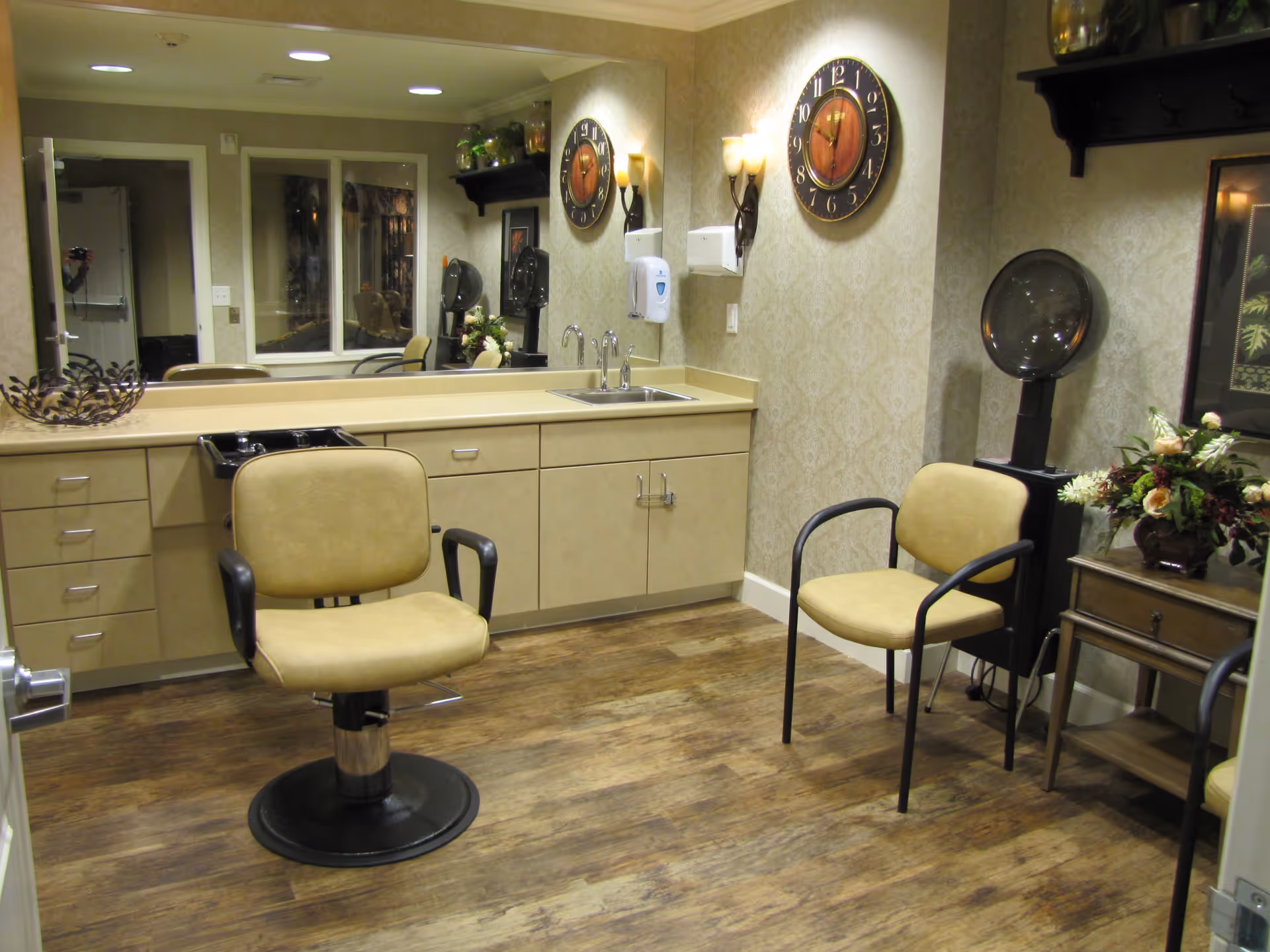 A salon-style interior with styling chairs, a sink and mirror, cabinets, and a wall clock.