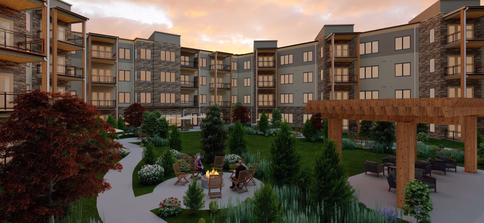 Outdoor courtyard area of a senior living facility with a large green lawn, walking paths, trees, shrubs, and flowers. There are seating areas including chairs around a fire pit and under a wooden pergola. The multi-story building with balconies surrounds the courtyard under a partly cloudy sky at sunset.