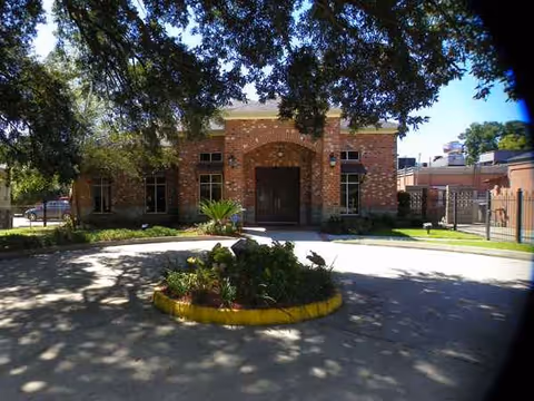 Brick nursing facility entrance with circular landscaped island and surrounding trees