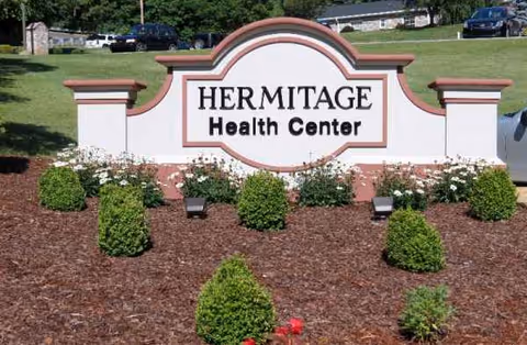 Front sign reading Hermitage Health Center with trimmed shrubs and mulch.
