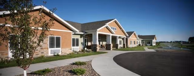 Exterior view of Bluffview Memory Care showing single-story cottages, a curved driveway, and landscaped front.