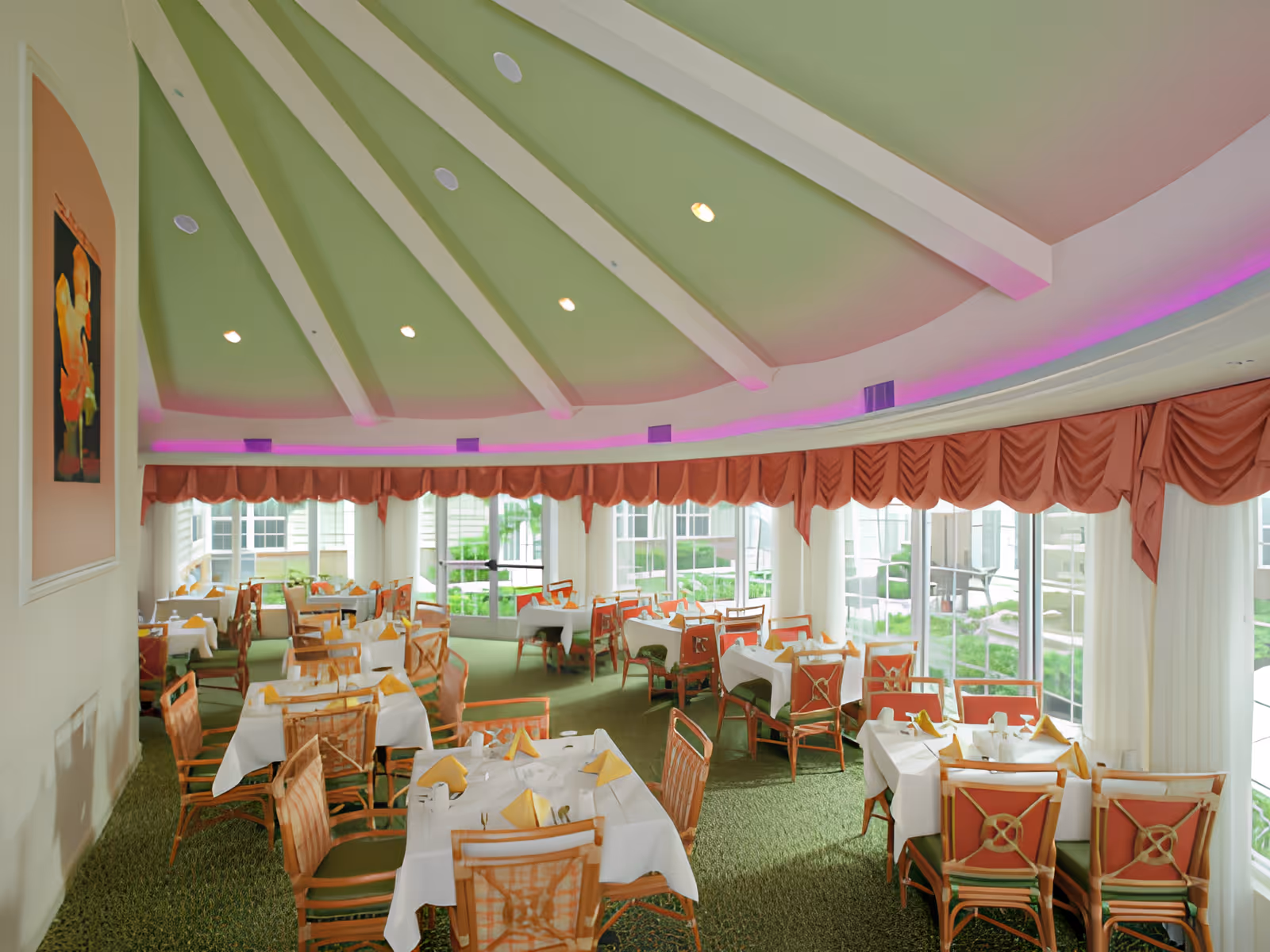 Bright dining room with multiple set tables and chairs under a domed ceiling and large windows.