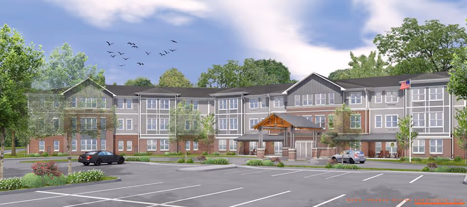Front exterior rendering of a three-story senior living building with a covered entrance, parking lot, landscaping and an American flag.