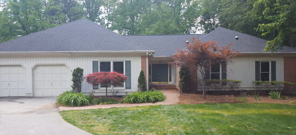 Single-story senior living facility exterior with a two-car garage and landscaped front yard.