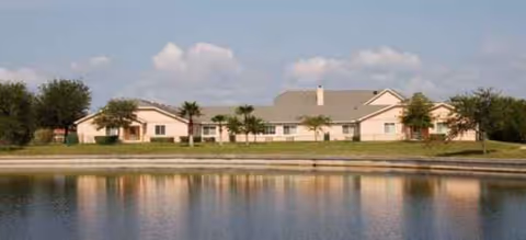 Brookdale Punta Gorda Isles exterior, a single-story building beside a calm pond and trees.