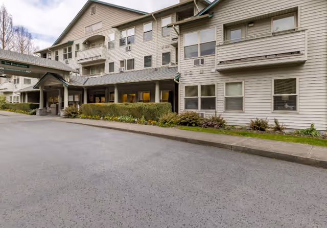 Exterior front view of Village Green Federal Way senior living building with a covered entrance.