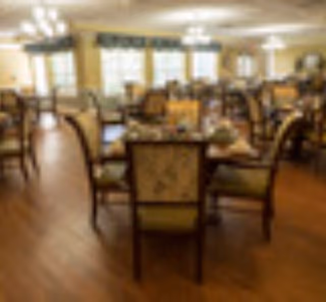 Large dining room with multiple set tables and upholstered chairs on a wood floor.