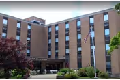 Brick nursing facility exterior with entrance, sign, and flagpole.