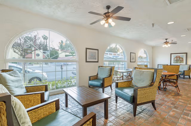Sunny common lounge with wicker armchairs, a coffee table and arched windows overlooking the street.