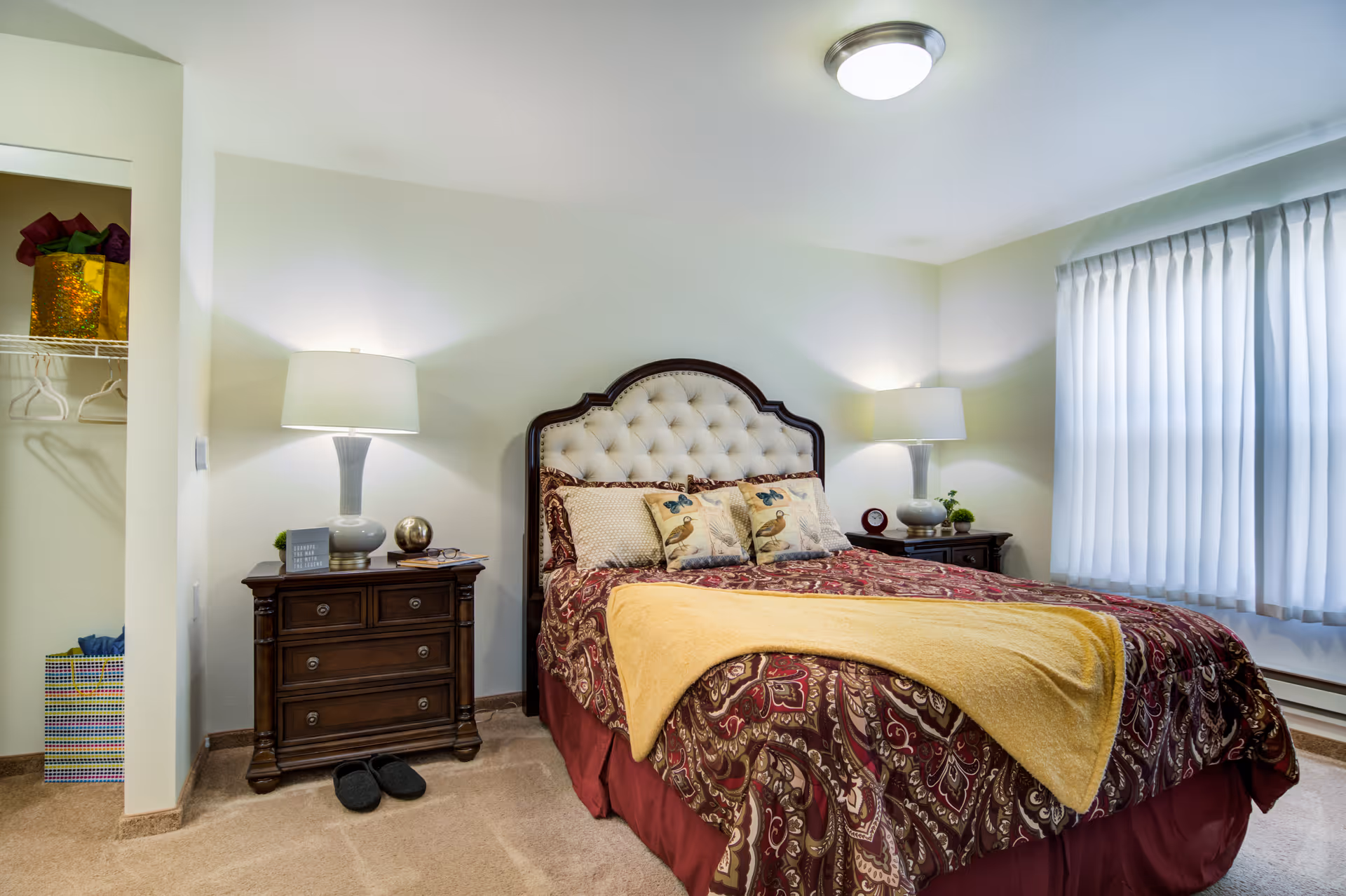 Cozy bedroom with a tufted headboard, patterned bedding and two bedside tables with lamps.