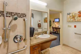 Accessible bathroom with sink, mirror, grab bars, and doorway to a living area.