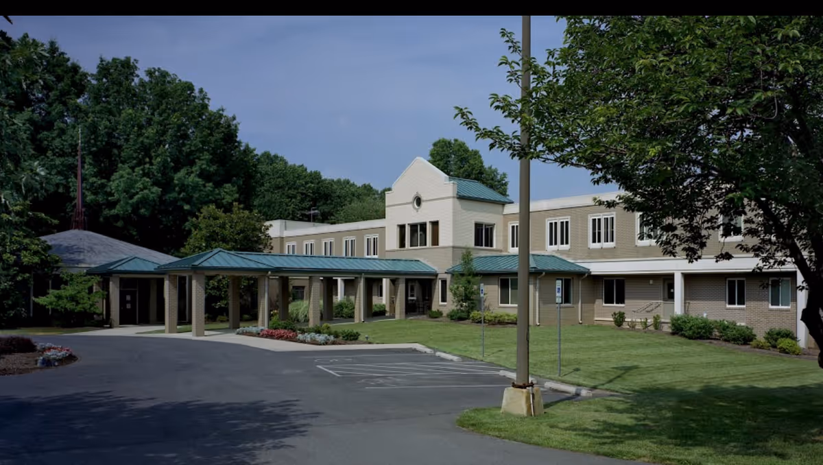 Exterior view of Marian Assisted Living with a covered entrance, green lawn, and parking area.