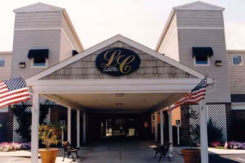 Front entrance of Lexington Commons senior living facility with flags and seating.