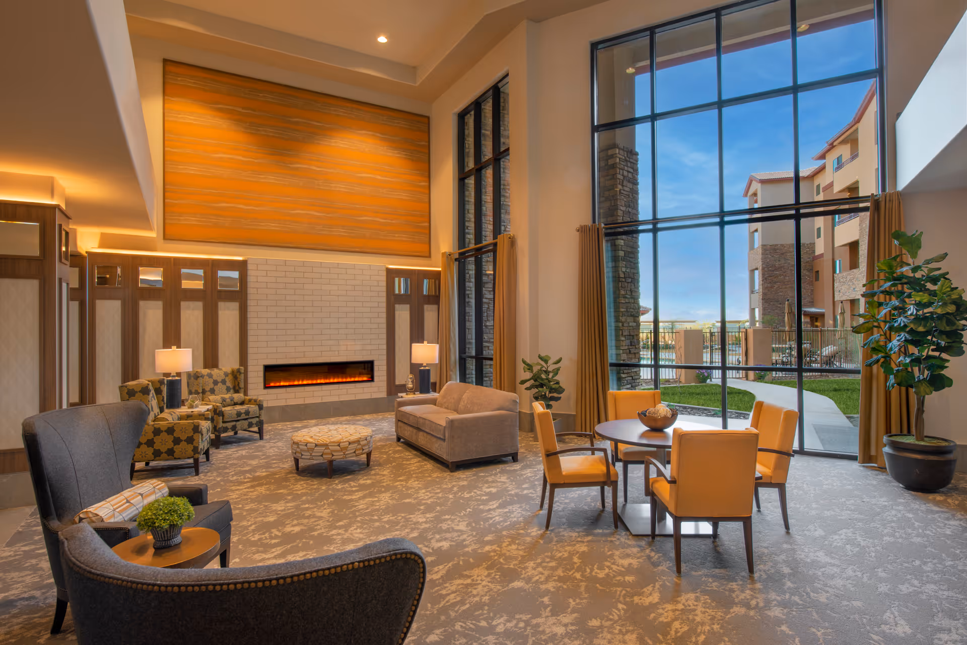 Spacious, well-lit lounge with multiple seating areas, a fireplace, tall windows, and a table with chairs.